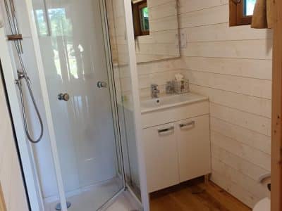 Salle de bain moderne dans un hébergement insolite en bois, avec douche et lavabo.