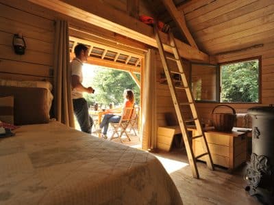 Cabane en bois avec terrasse, lumière naturelle et ambiance chaleureuse.