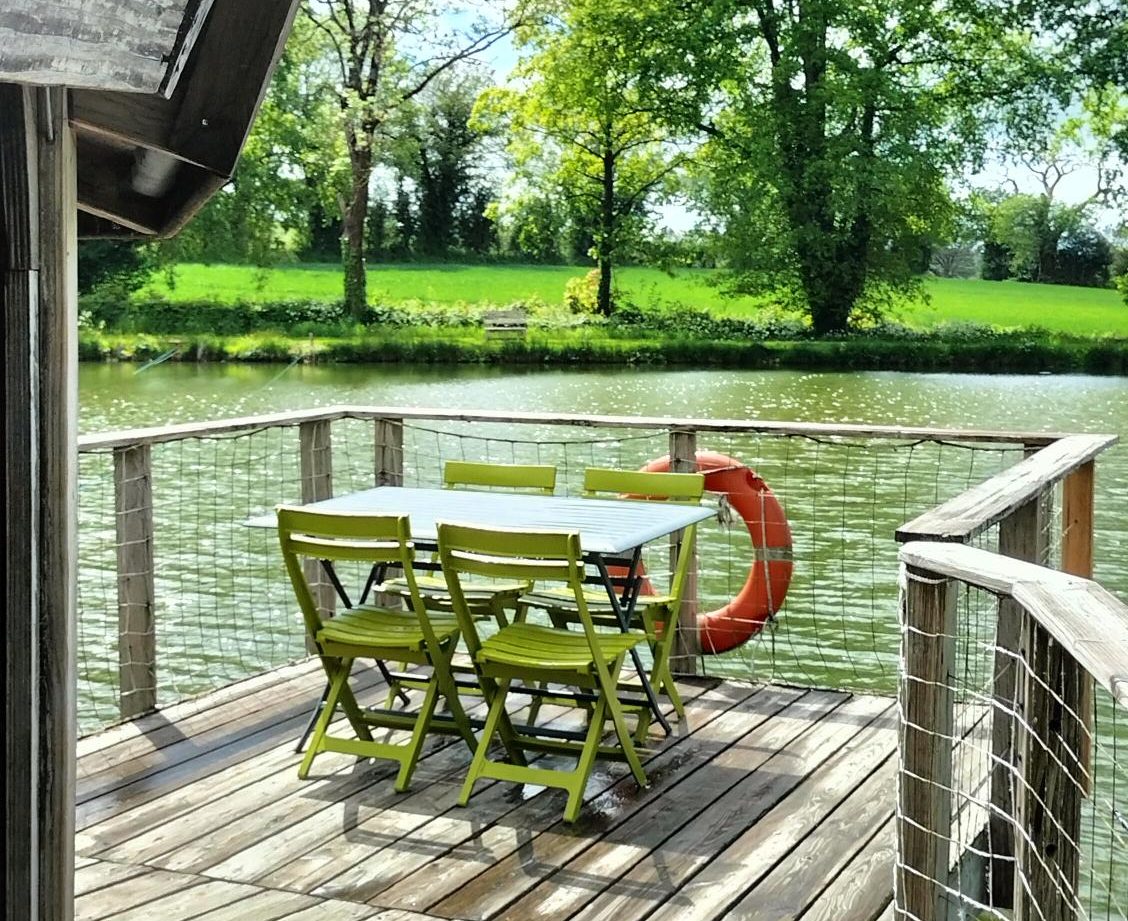 Cabane flottante en Pays de la Loire, avec une terrasse en bois surplombant leau.