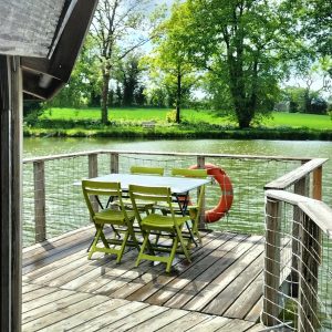 Cabane flottante en Pays de la Loire, avec une terrasse en bois surplombant leau.