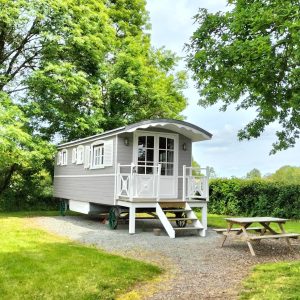 Charmante roulotte à Pays de la Loire, entourée de verdure et dun coin repas extérieur.