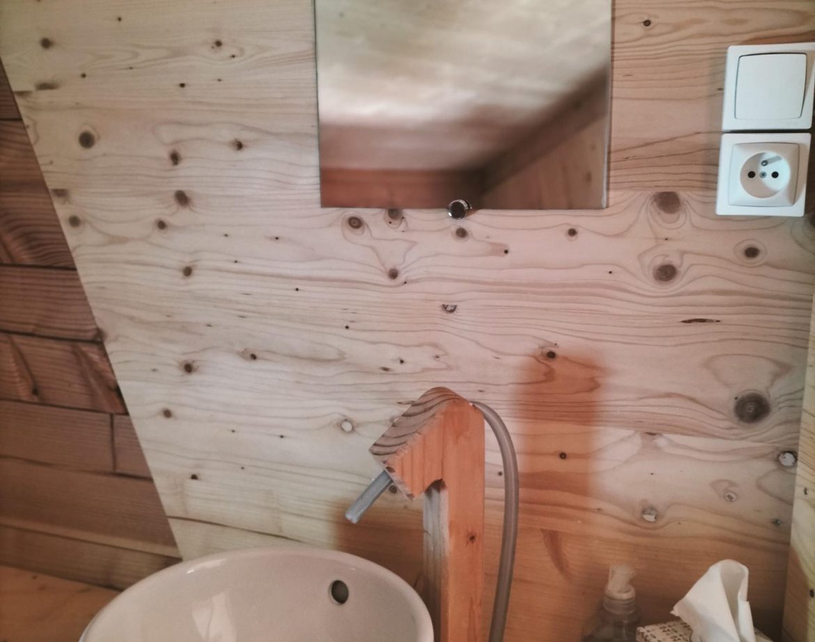 Élégante cabane en bois avec lavabo moderne et miroir, ambiance chaleureuse.