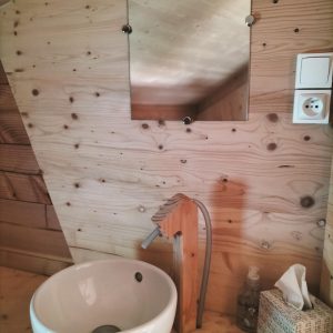 Élégante cabane en bois avec lavabo moderne et miroir, ambiance chaleureuse.
