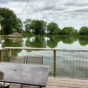 Cabane flottante au bord dun lac, avec une terrasse et vue sur la nature verdoyante.
