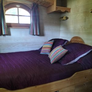 Chalet en bois dans les Pays de la Loire, lit douillet avec coussins colorés.