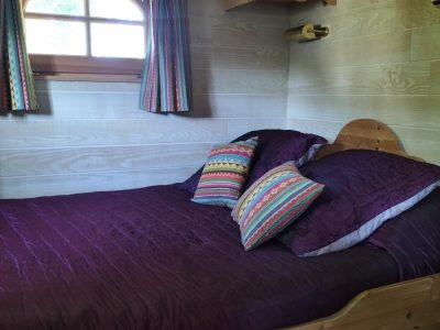 Chalet en bois dans les Pays de la Loire, lit douillet avec coussins colorés.