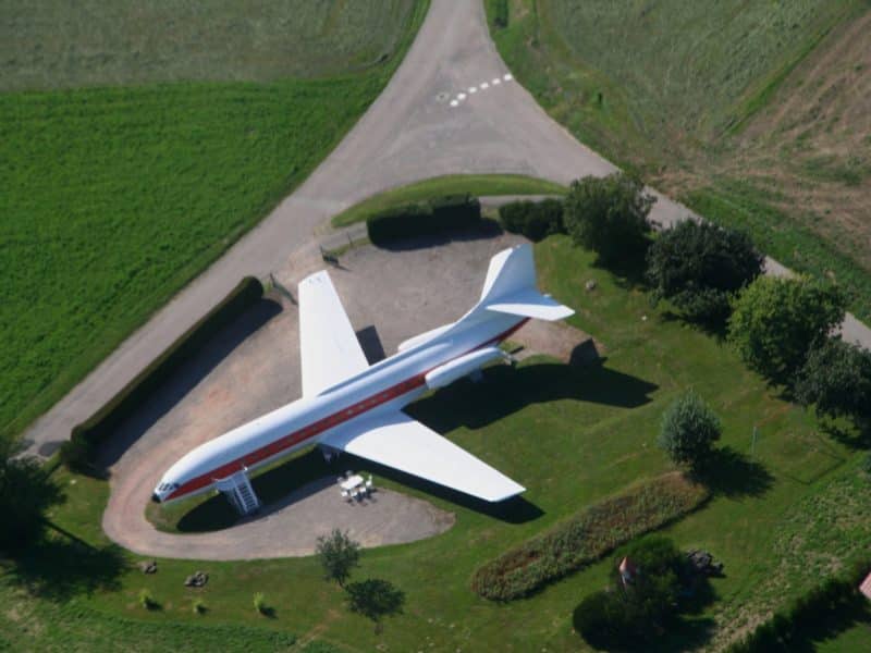 Hébergement insolite dans un avion vintage, entouré de verdure et dun chemin sinueux.