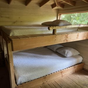Chalet en bois avec lits superposés, ambiance chaleureuse et naturelle.