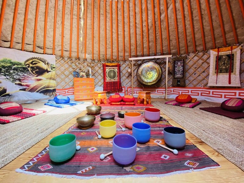 Yourte accueillante avec décor zen, bols chantants colorés et ambiance relaxante.