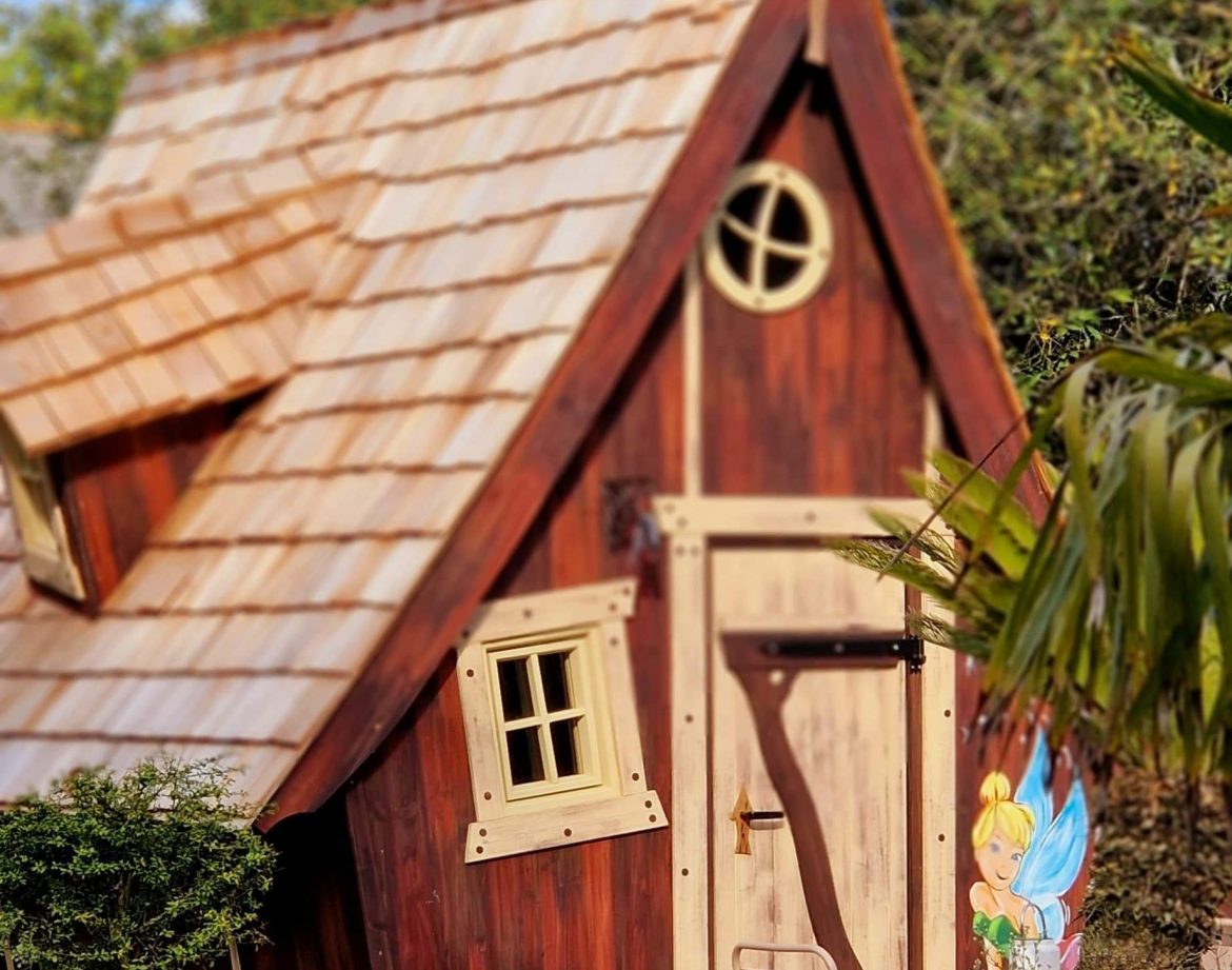 Cabane en bois avec toit en ardoise et décoration féerique à lextérieur.