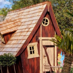 Cabane en bois avec toit en ardoise et décoration féerique à lextérieur.
