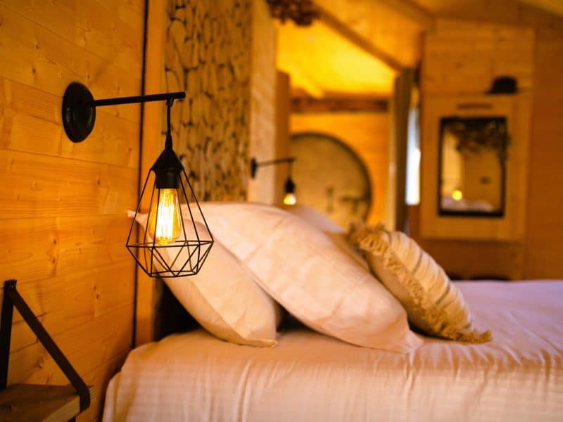 Chalet en bois chaleureux avec lampes suspendues et literie douillette.
