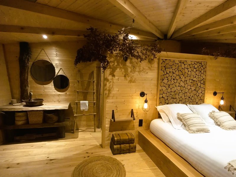 Chalet en bois chaleureux avec lit douillet et décoration naturelle apaisante.