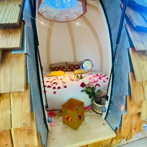 Cabane en bois romantique en Bretagne, décorée de pétales de roses et lumière douce.