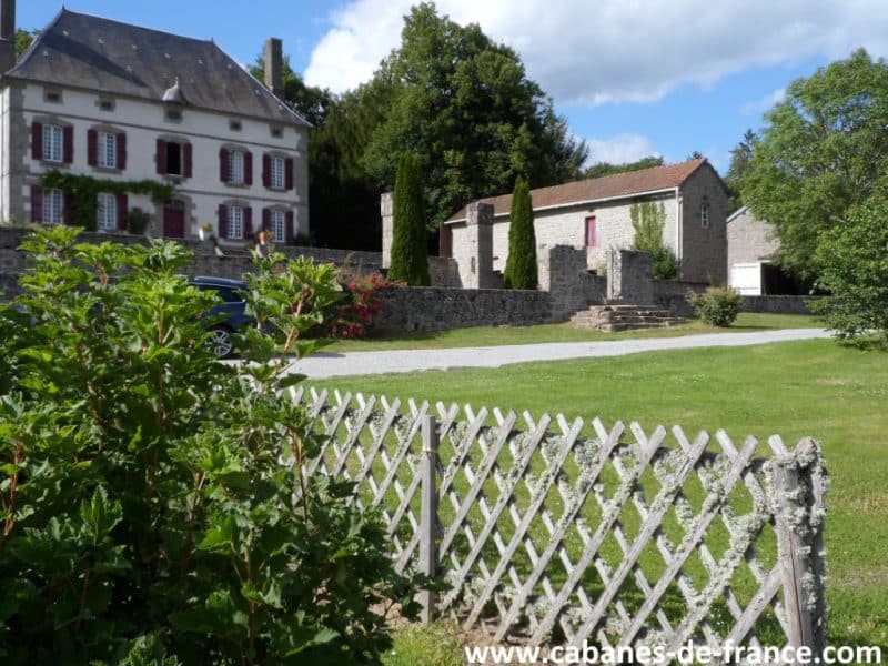 Charmante maison dhôtes avec volets rouges et jardin verdoyant.