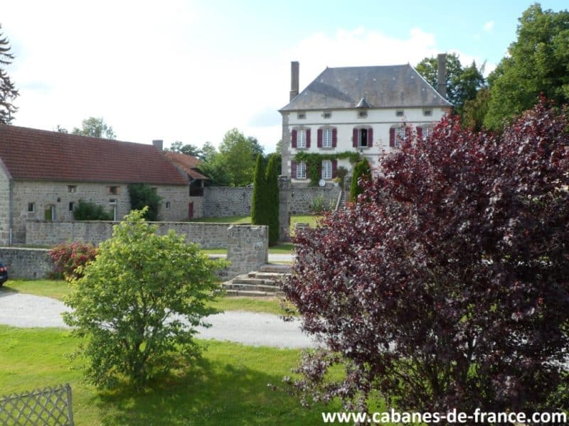 Charmante maison de campagne avec jardin verdoyant et arbres colorés.