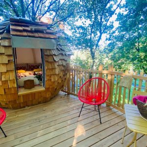 Cabane en bois en Bretagne, avec un lit douillet et des chaises colorées.