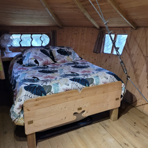 Chalet en bois avec lit douillet et décor tropical, situé en Pays de la Loire.