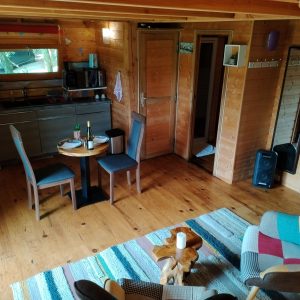 Cabane en bois à Aquitaine, intérieur chaleureux avec mobilier coloré et coin repas.
