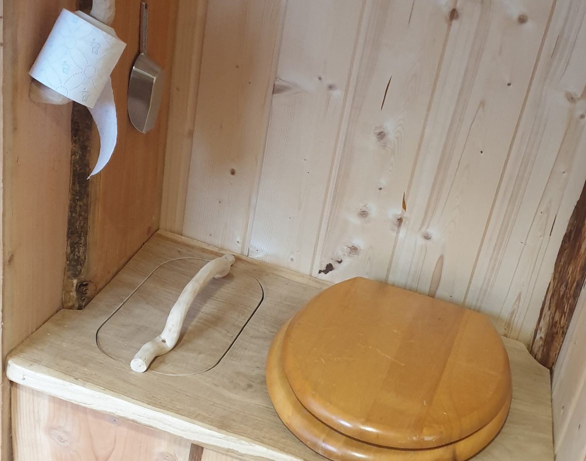 Toilettes en bois dans un hébergement insolite en Auvergne-Rhône-Alpes. Ambiance chaleureuse.