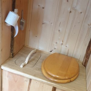 Toilettes en bois dans un hébergement insolite en Auvergne-Rhône-Alpes. Ambiance chaleureuse.