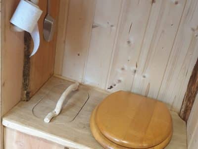 Toilettes en bois dans un hébergement insolite en Auvergne-Rhône-Alpes. Ambiance chaleureuse.