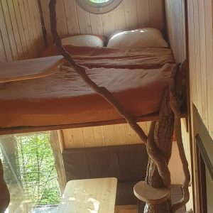 Cabane perchée en bois avec un lit douillet et une vue sur la nature.