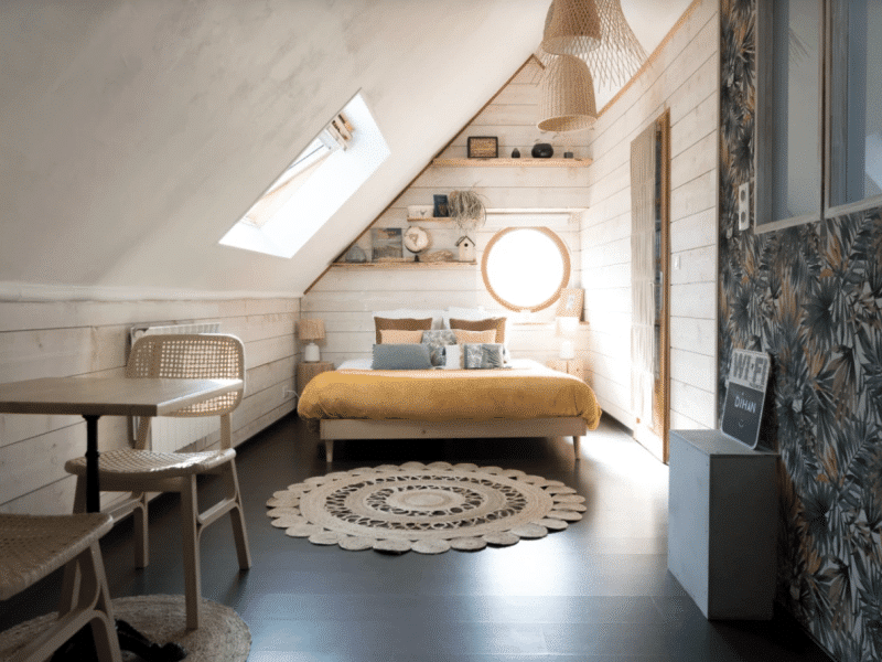 Chambre cosy en Bretagne avec un lit douillet et une grande fenêtre ronde.