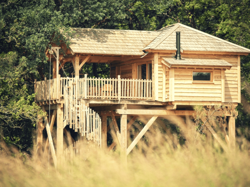Cabane perchée en bois, avec balcon et vue sur la nature environnante en Bretagne.