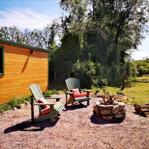 Hébergement insolite en Bourgogne : chalet en bois avec chaises confortables et feu de camp.