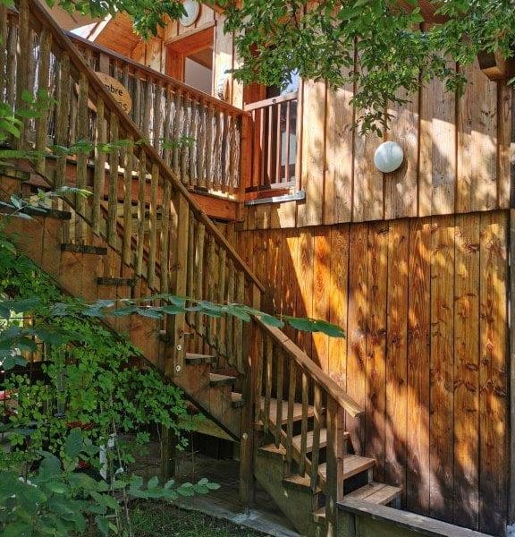 Chalet en bois avec un escalier en bois et des détails naturels environnants.