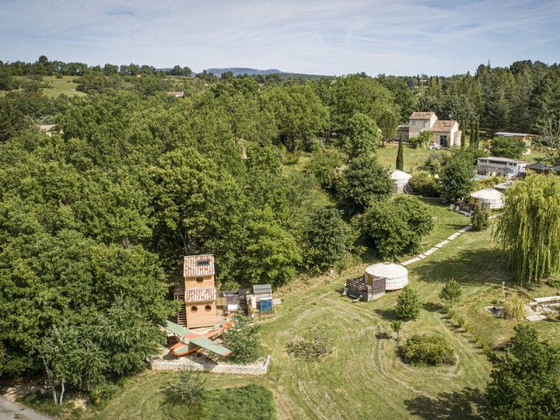 Écolodge en pleine nature, entouré darbres verdoyants et de chemins sinueux.