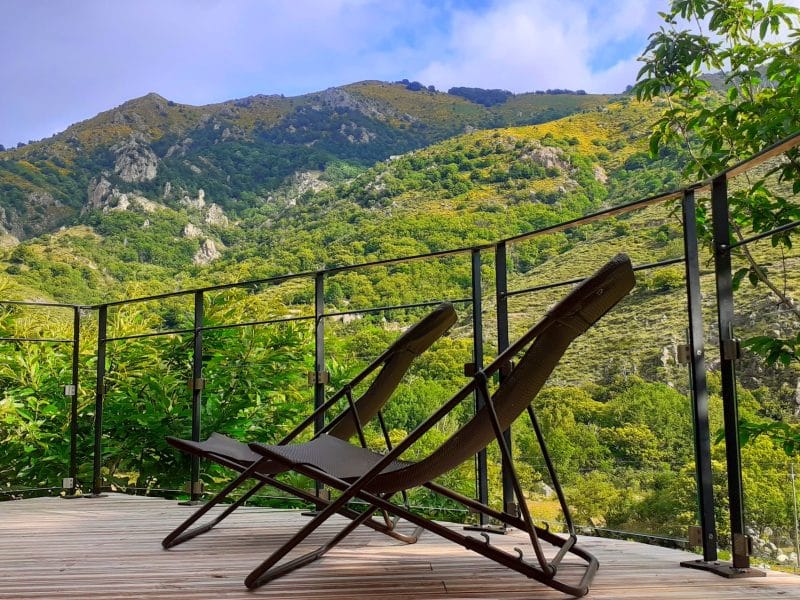 Chalet en pleine nature avec chaises longues et vue sur les montagnes verdoyantes.