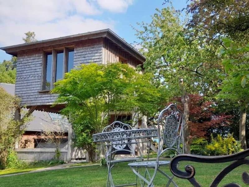Charmante maison en bois avec jardin verdoyant et mobilier en fer forgé.