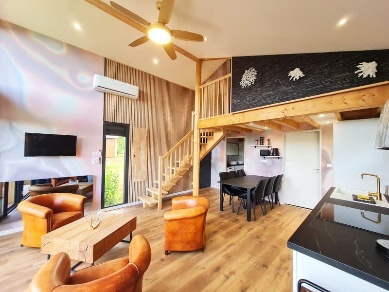 Chalet moderne avec salon lumineux, escalier en bois et décoration élégante.