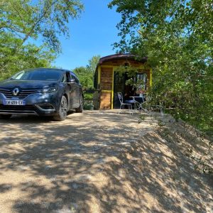 Hébergement insolite en Auvergne : une roulotte colorée entourée de verdure.