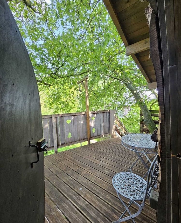 Cabane perchée en Hauts-de-France avec terrasse en bois et vue sur la nature.