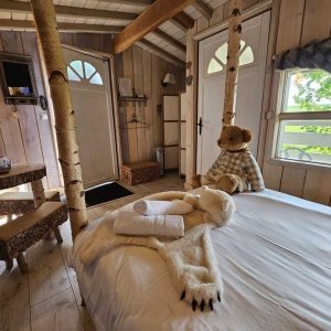 Cabane en bois avec des troncs darbre, décorée dours en peluche. Confort et charme.