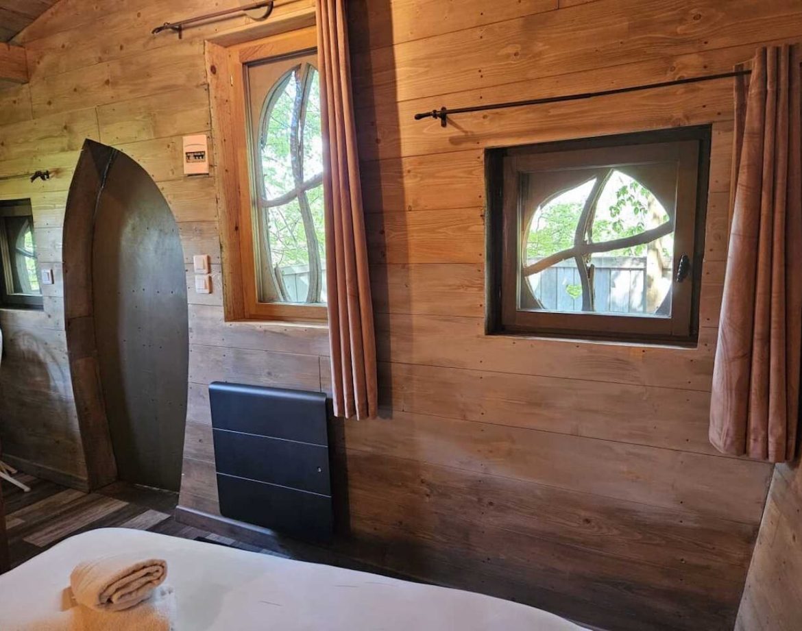 Hébergement insolite en bois avec fenêtres arrondies et ambiance chaleureuse.