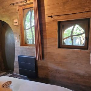 Hébergement insolite en bois avec fenêtres arrondies et ambiance chaleureuse.