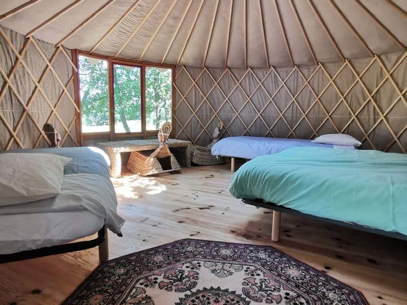 Yourte spacieuse avec un plafond en dôme et des lits confortables. Ambiance chaleureuse.