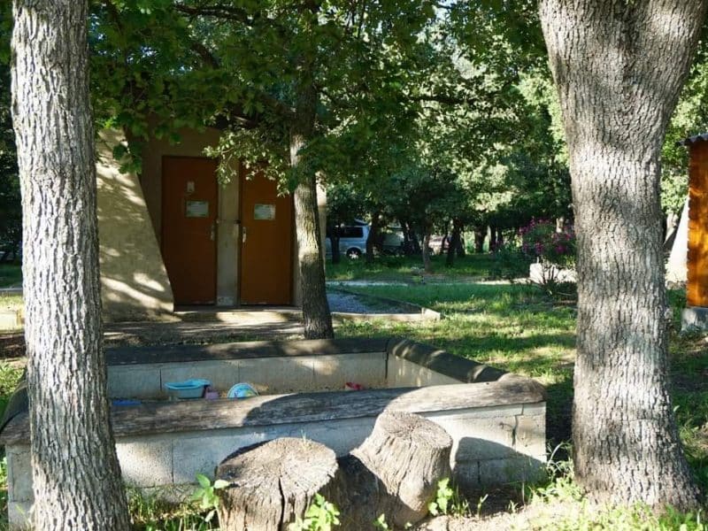 Cabane en bois entourée darbres, avec une aire de jeux pour enfants.