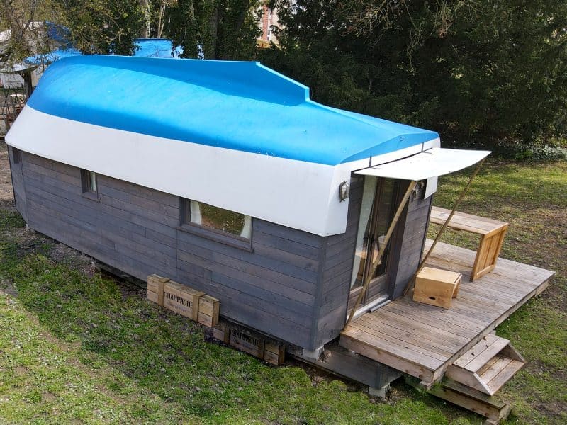 Hébergement insolite en forme de bateau à Champagne-Ardennes, avec terrasse en bois.