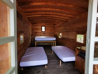 Cabane en bois dans les Alpes, intérieur chaleureux avec lits simples et fenêtres.
