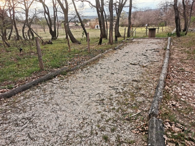 Chemin de terre menant à un gîte rural, entouré darbres et de verdure.