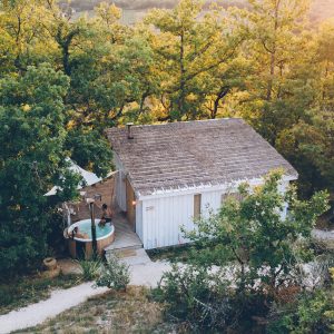 Cabane en bois avec jacuzzi, entourée darbres verdoyants en Midi-Pyrénées.
