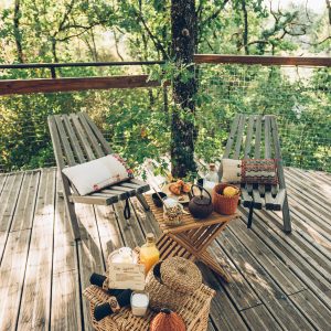Cabane perchée en Midi-Pyrénées, avec chaises en bois et décor naturel accueillant.