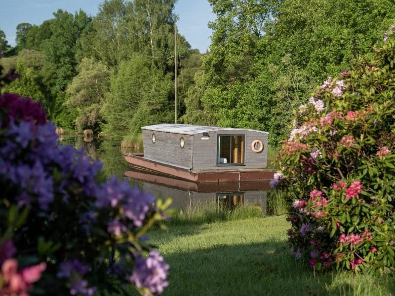 Hébergement insolite : une maison flottante entourée de fleurs colorées au bord de leau.