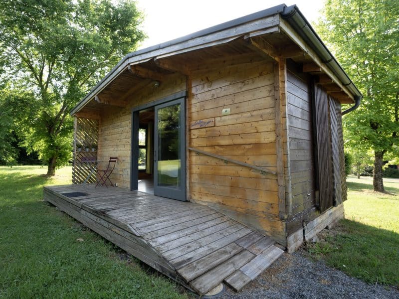 Cabane en bois à Limousin, entourée darbres verdoyants et dun espace extérieur.