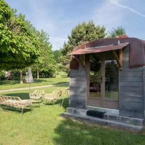 Cabane en bois à Limousin, avec un toit en métal et des chaises confortables à lextérieur.